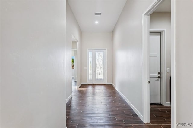 doorway with wood tiled floor, visible vents, and baseboards