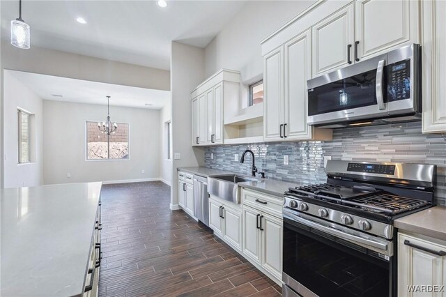 kitchen with appliances with stainless steel finishes, white cabinets, a sink, and pendant lighting