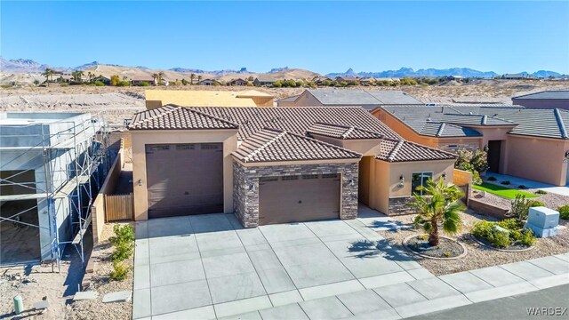 view of front of house featuring a garage, stone siding, a tile roof, and a mountain view