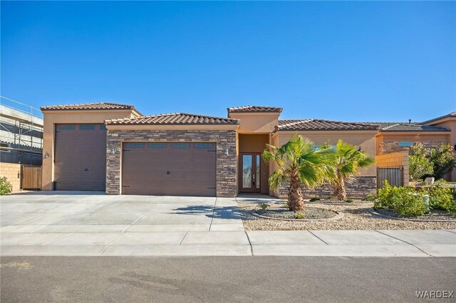 view of front of property featuring an attached garage, a tile roof, stone siding, concrete driveway, and stucco siding