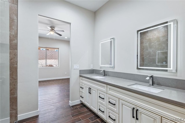 full bath with wood finish floors, a sink, baseboards, and double vanity