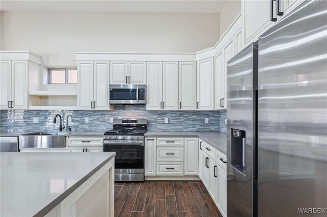 kitchen featuring stainless steel appliances, white cabinetry, a sink, and tasteful backsplash