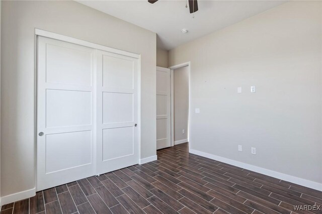 unfurnished bedroom with baseboards, ceiling fan, a closet, and wood tiled floor