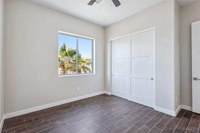 unfurnished bedroom featuring wood tiled floor, a closet, ceiling fan, and baseboards