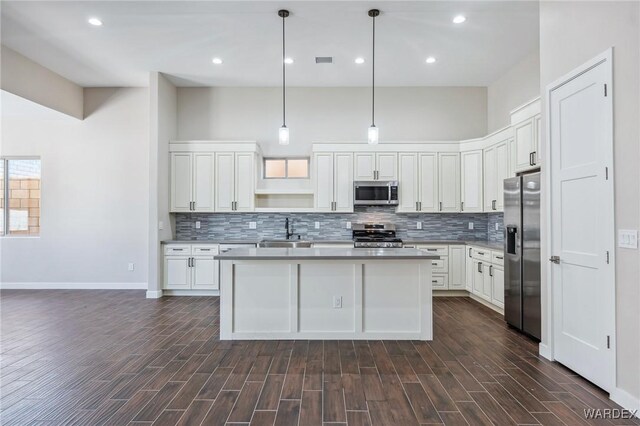 kitchen featuring stainless steel appliances, light countertops, a center island, and pendant lighting