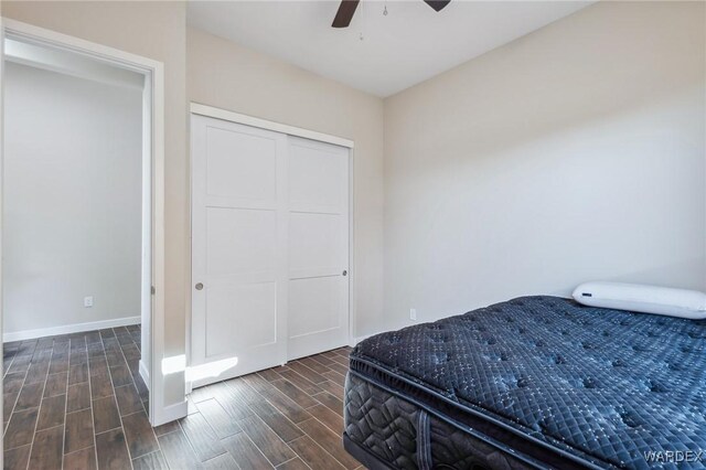 bedroom featuring wood finish floors, a closet, ceiling fan, and baseboards