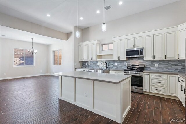 kitchen featuring appliances with stainless steel finishes, a kitchen island, visible vents, and pendant lighting