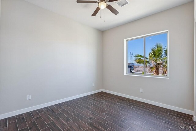 empty room with visible vents, dark wood finished floors, baseboards, and ceiling fan