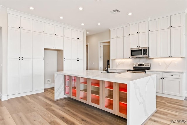 kitchen with a spacious island, a sink, visible vents, white cabinets, and appliances with stainless steel finishes