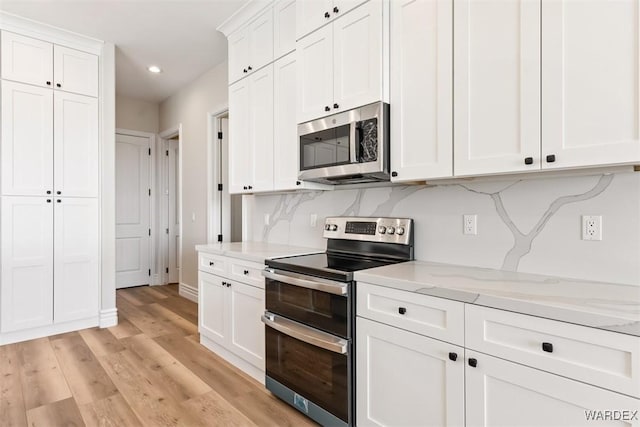 kitchen featuring appliances with stainless steel finishes, light wood-type flooring, white cabinetry, and backsplash