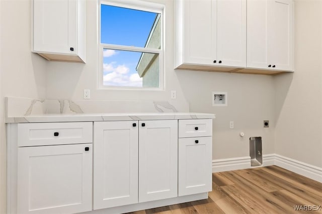 clothes washing area with hookup for a washing machine, cabinet space, light wood-style flooring, hookup for an electric dryer, and baseboards