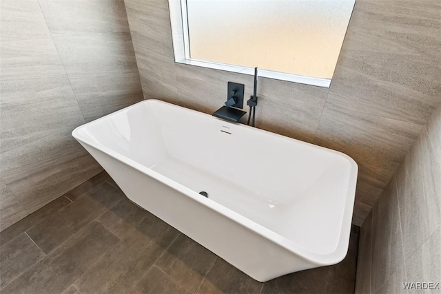 bathroom with a soaking tub and tile walls