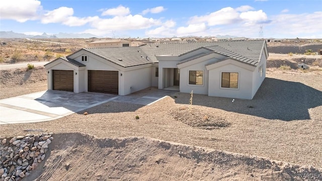 view of front facade with driveway, an attached garage, a tile roof, and stucco siding