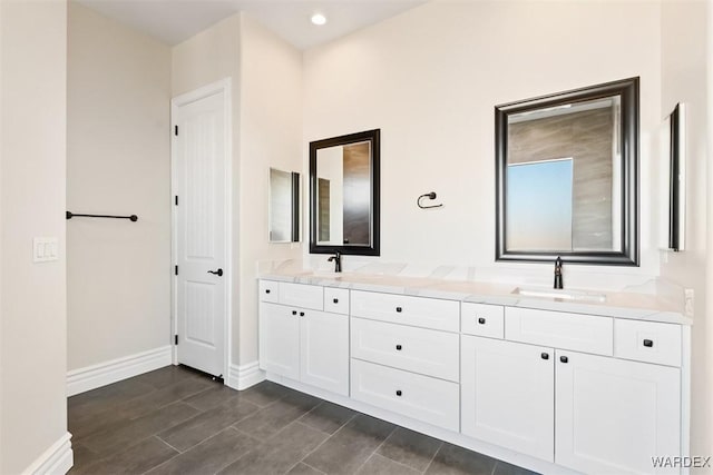 bathroom with double vanity, baseboards, a sink, and recessed lighting