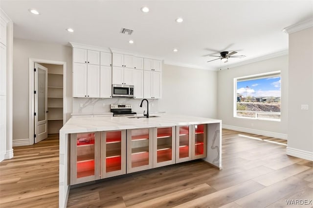 kitchen featuring stainless steel appliances, visible vents, a sink, and light wood-style flooring