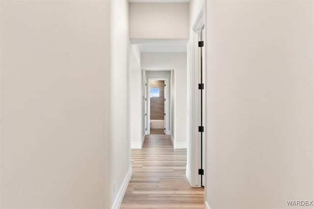 corridor with light wood-style flooring and baseboards