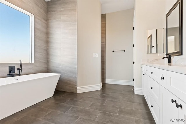 full bathroom with a freestanding tub, vanity, and baseboards