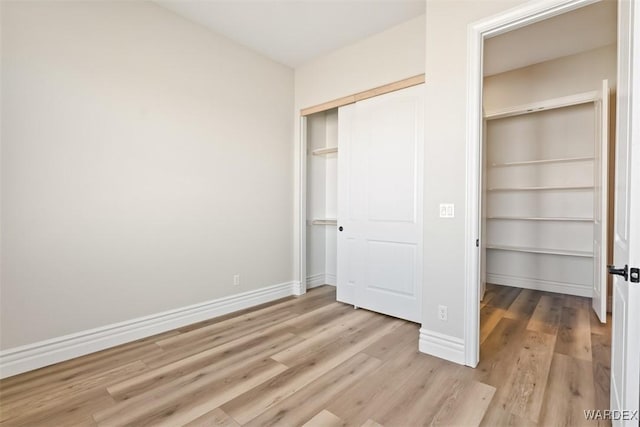 unfurnished bedroom with a closet, light wood-style flooring, and baseboards