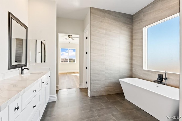 full bathroom with tile walls, a soaking tub, ceiling fan, vanity, and tile patterned floors