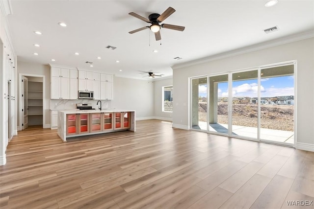 unfurnished living room featuring baseboards, light wood-type flooring, visible vents, and recessed lighting