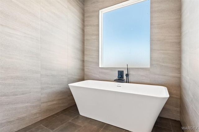 full bathroom featuring tile patterned flooring, a freestanding tub, and tile walls