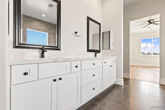 bathroom featuring double vanity, visible vents, ceiling fan, a sink, and baseboards