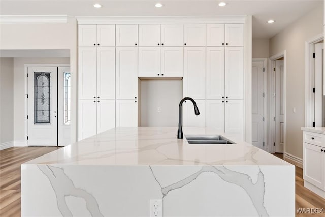 kitchen with light wood-type flooring, white cabinetry, a sink, and recessed lighting