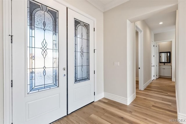 foyer featuring crown molding, light wood finished floors, and baseboards