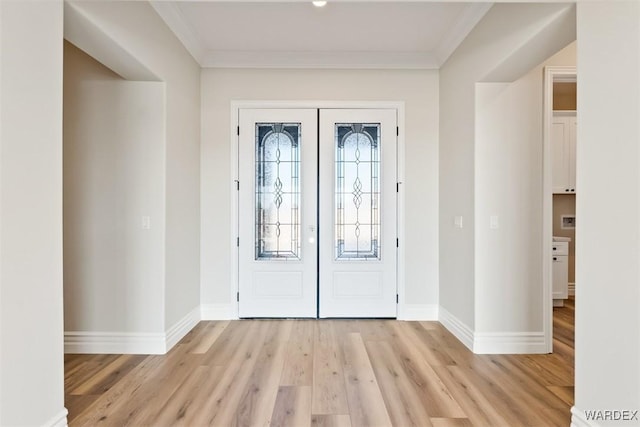 foyer entrance with light wood-style floors, baseboards, ornamental molding, and french doors