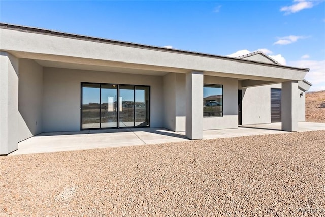 back of house with stucco siding and a patio