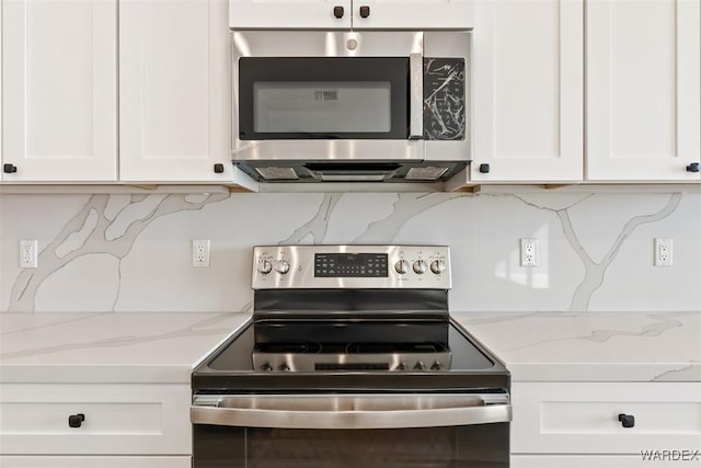 kitchen with tasteful backsplash, appliances with stainless steel finishes, light stone countertops, and white cabinets