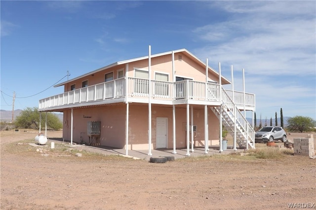 rear view of house featuring stairway, a deck, and stucco siding