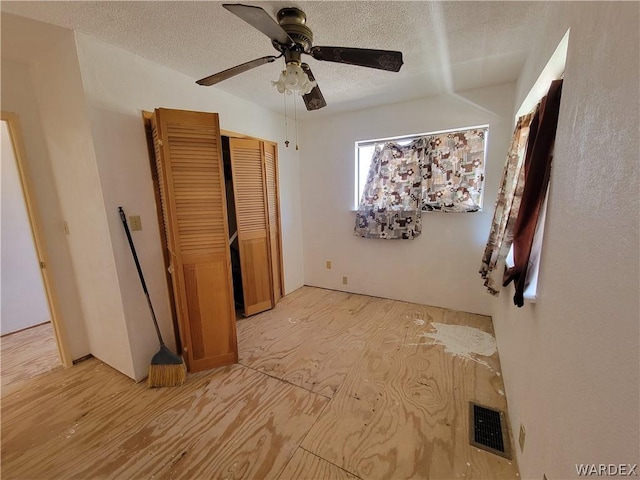 bedroom featuring ceiling fan, a closet, visible vents, and a textured ceiling