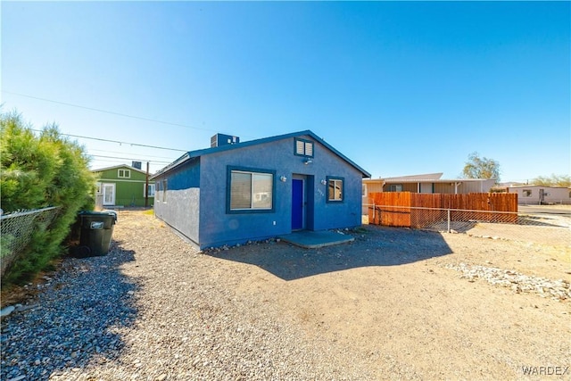 back of house featuring fence and stucco siding