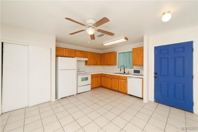 kitchen featuring white appliances, visible vents, brown cabinetry, light countertops, and a sink