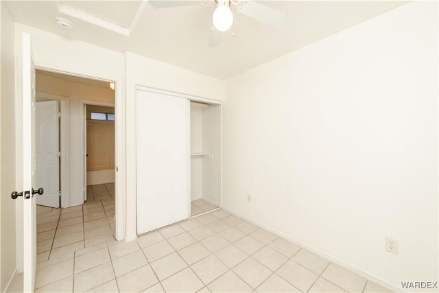 unfurnished bedroom featuring light tile patterned floors, baseboards, a ceiling fan, and a closet