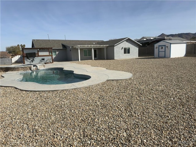 back of house with an outbuilding, stucco siding, an outdoor pool, a storage unit, and a patio area