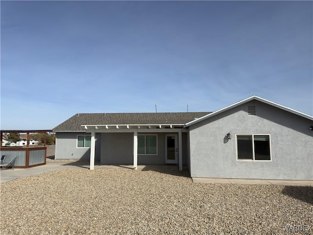 back of property with a patio area, a storage shed, stucco siding, and an outbuilding