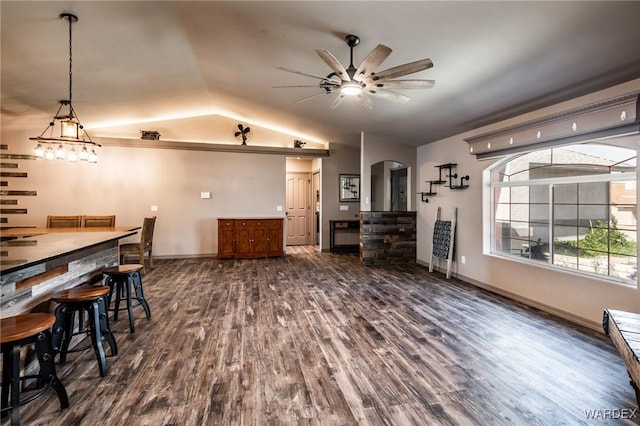 dining space with arched walkways, baseboards, dark wood-style floors, ceiling fan, and vaulted ceiling