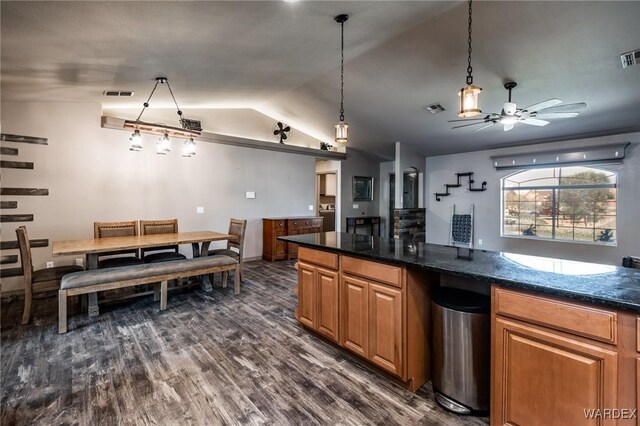 kitchen featuring dark wood-style floors, lofted ceiling, visible vents, brown cabinetry, and a ceiling fan