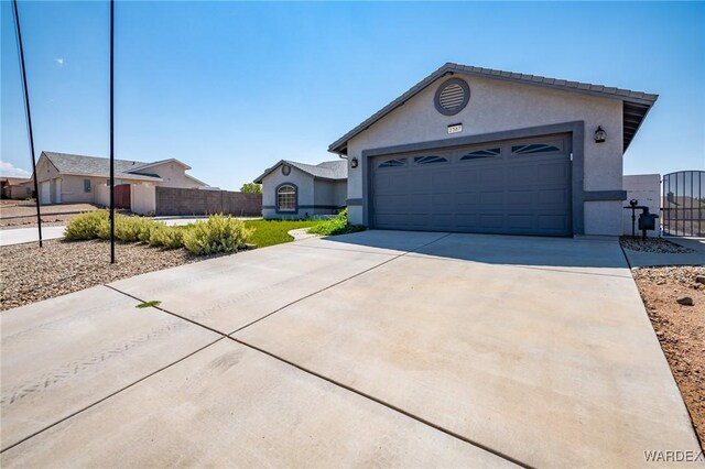 ranch-style house featuring a garage, concrete driveway, fence, and stucco siding