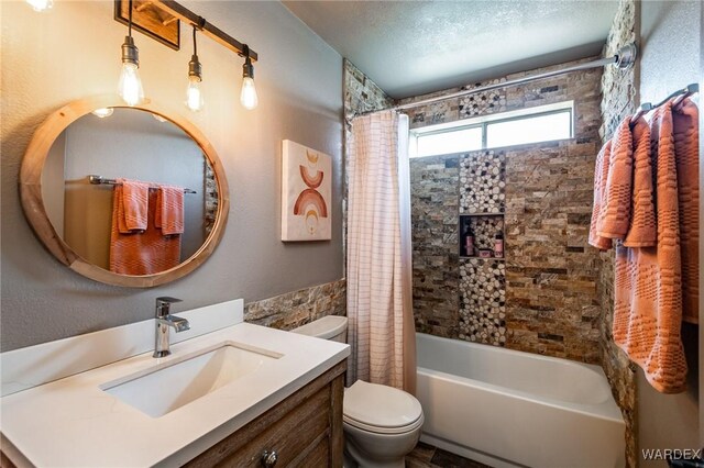 full bathroom with shower / tub combo with curtain, a textured ceiling, toilet, and vanity