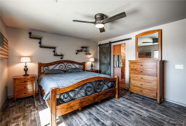 bedroom featuring a ceiling fan, wood finished floors, and a barn door