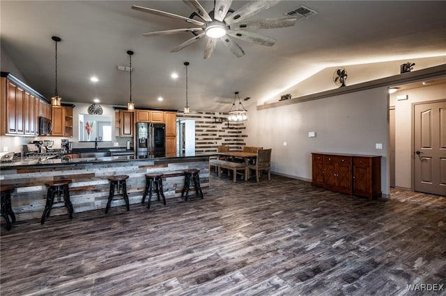 kitchen with visible vents, dark countertops, lofted ceiling, a breakfast bar area, and black fridge