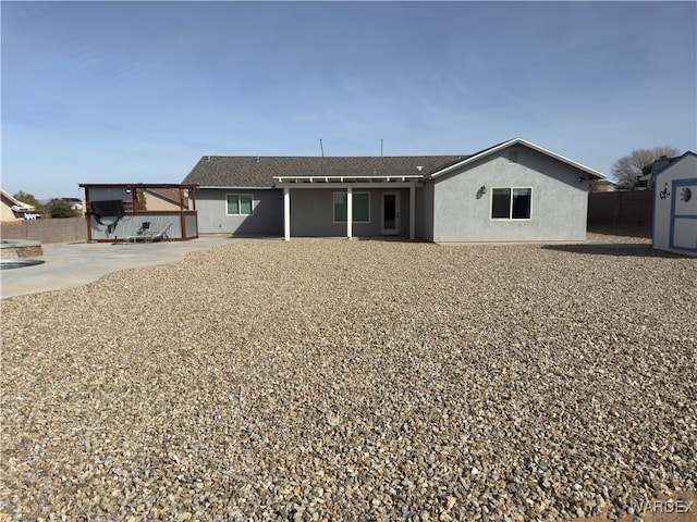 rear view of property featuring a patio area, fence, and stucco siding