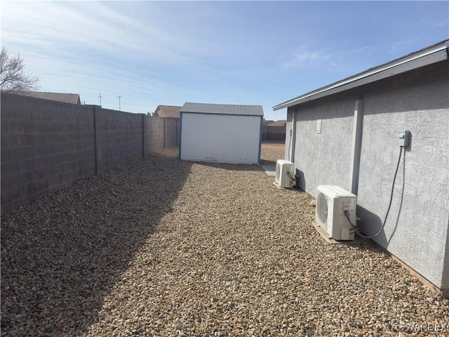 view of yard with an outbuilding, a storage unit, ac unit, and a fenced backyard