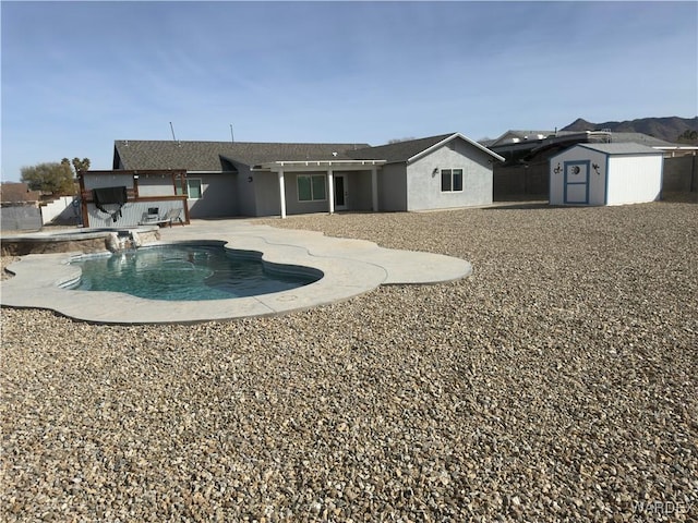 back of house featuring an outbuilding, a storage shed, a patio, stucco siding, and an outdoor pool