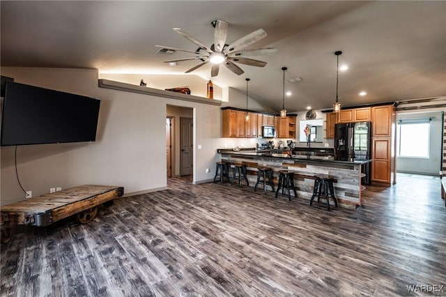 kitchen featuring dark wood-type flooring, dark countertops, stainless steel microwave, and a peninsula