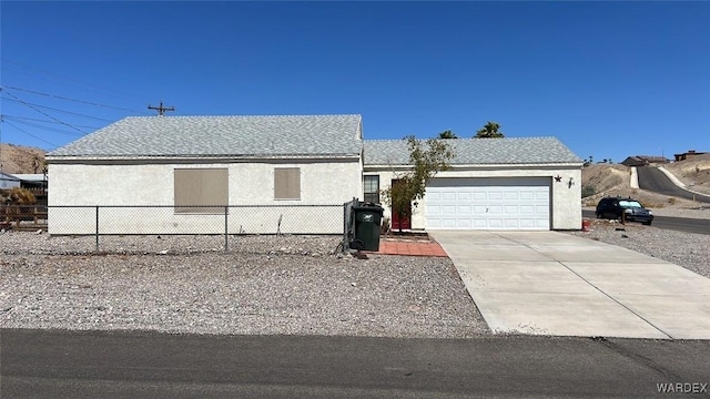 view of front of home featuring roof with shingles, stucco siding, fence, a garage, and driveway