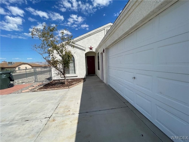 doorway to property with fence, driveway, and stucco siding